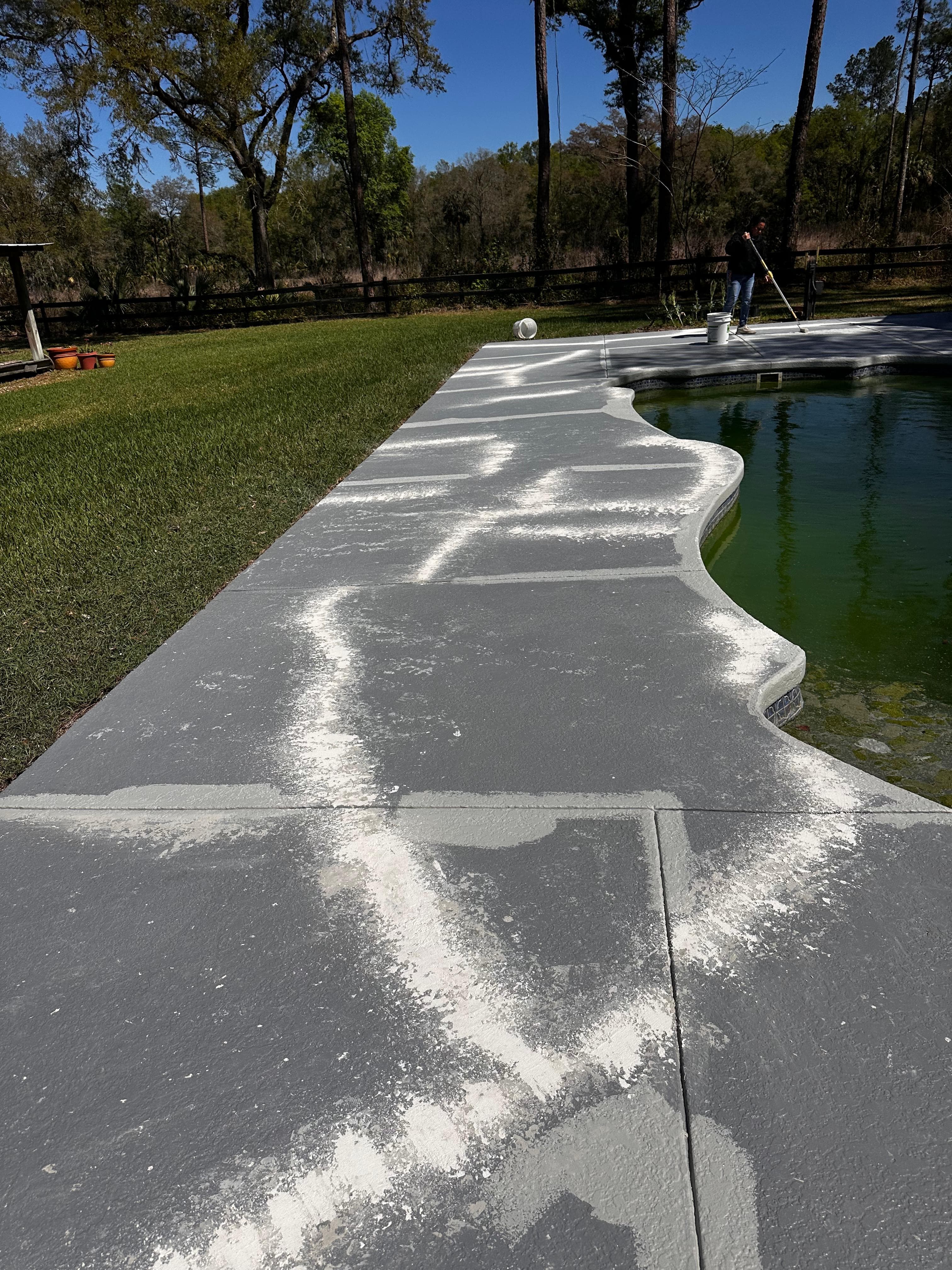 Professional applying deck coating to concrete pool deck — Florida