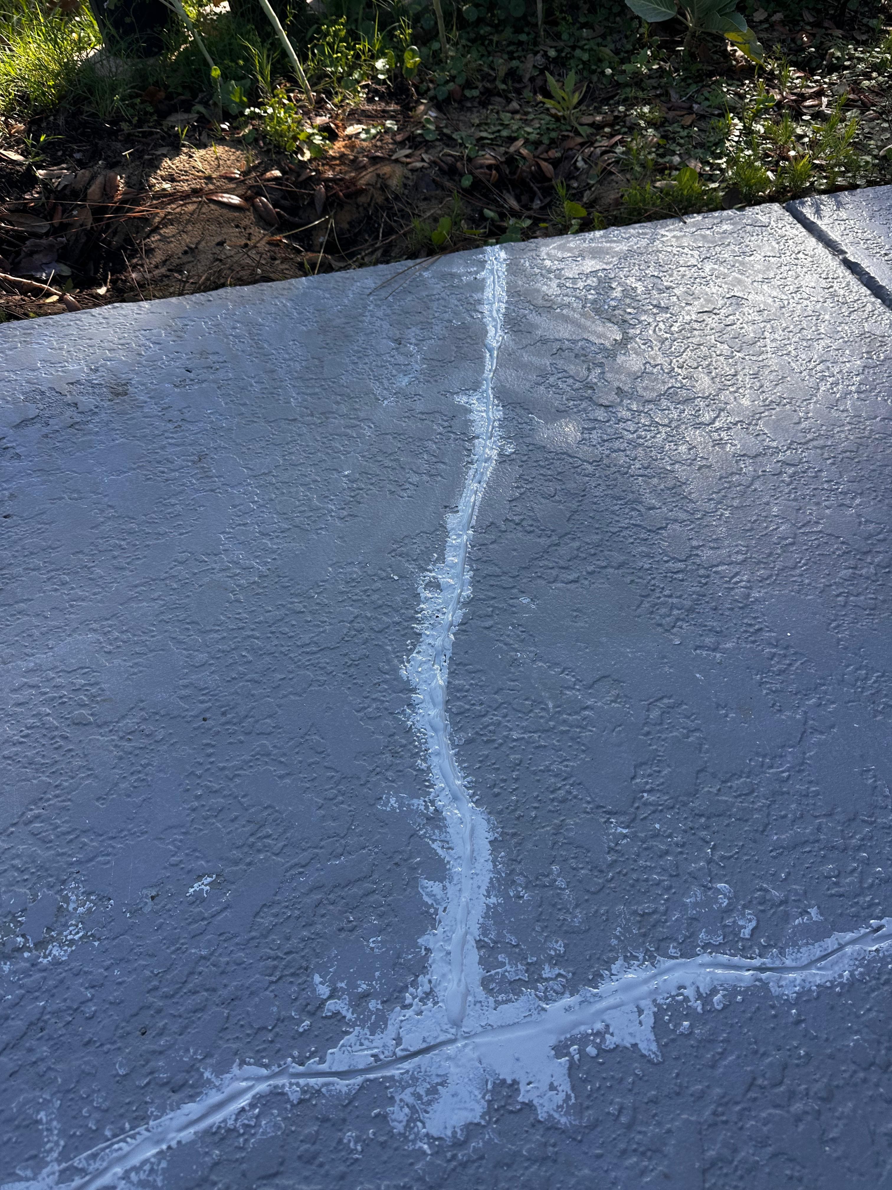 Concrete pool deck crack being filled with repair compound