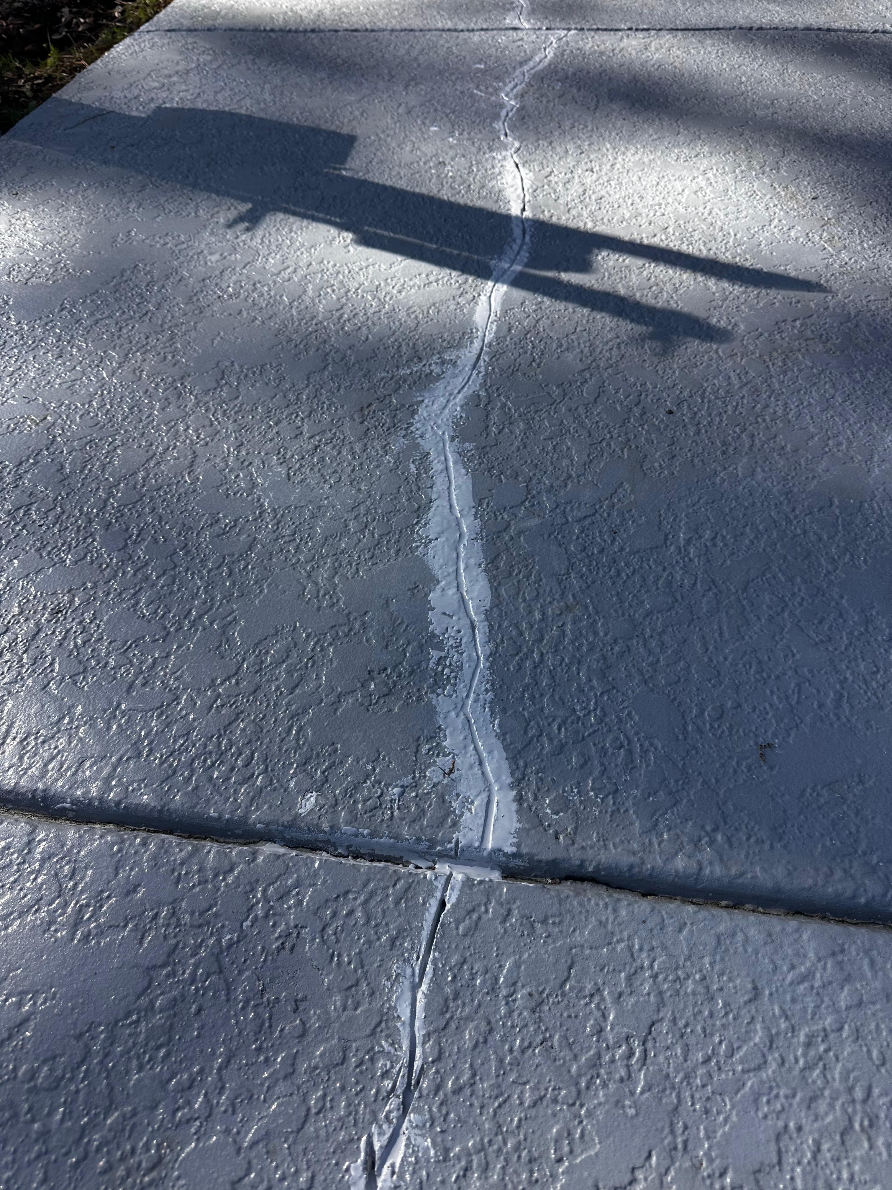 Cracked concrete pool deck before repair — multiple cracks visible
