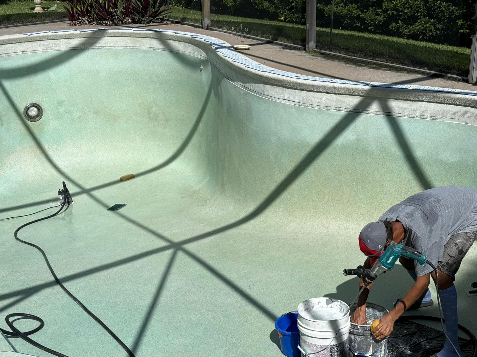 Professional tile installer working on pool step installation with precision tools