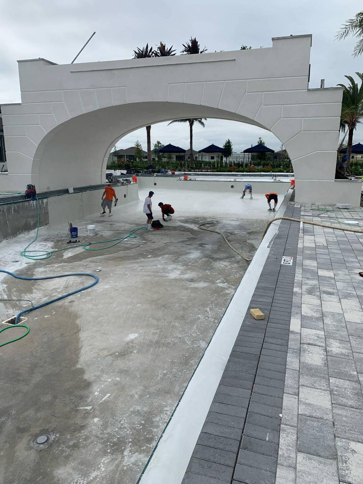 Commercial pool resurfacing in progress - professional team applying new surface finish on large commercial pool