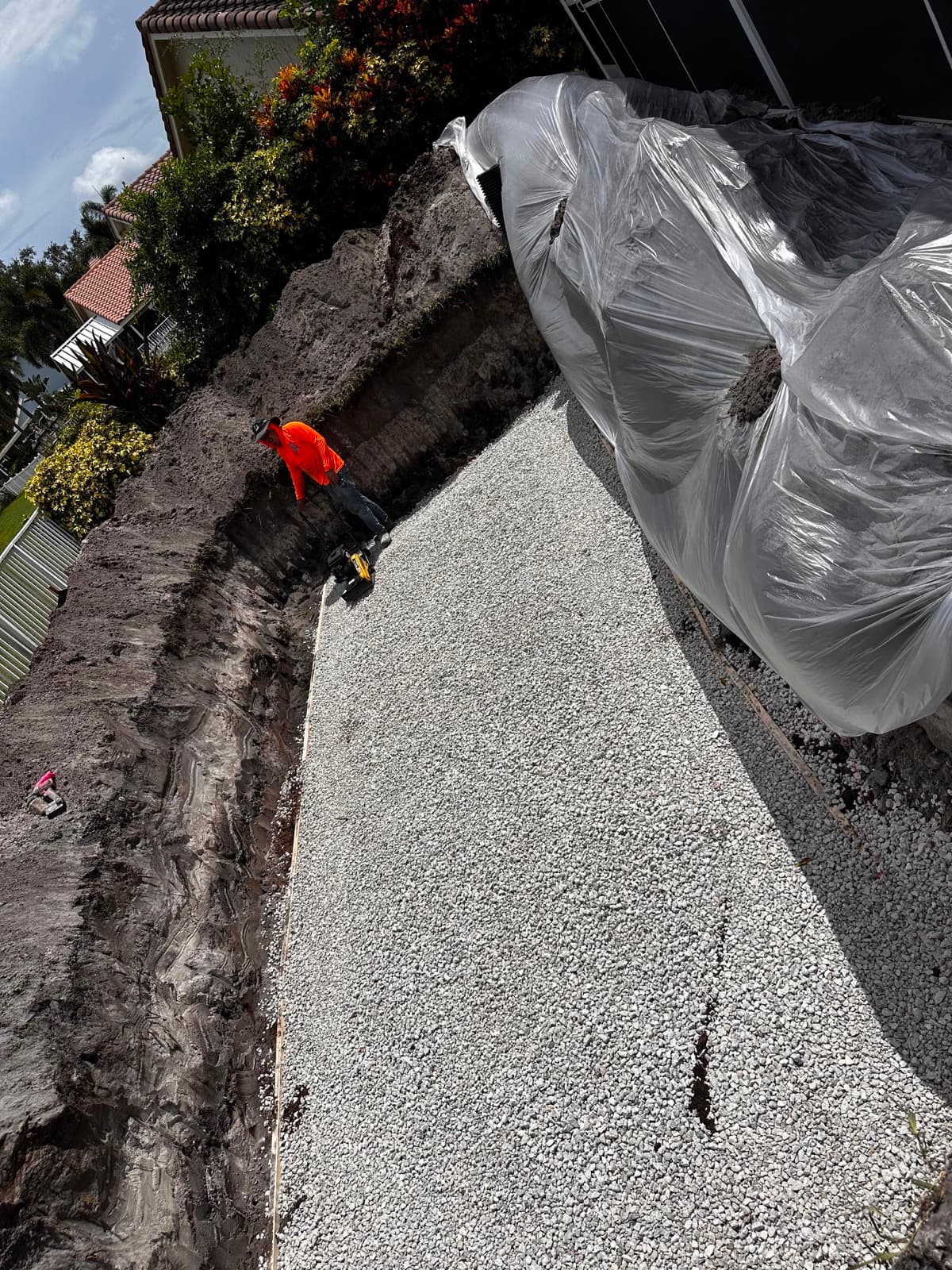 Cool Pool of Florida crew leveling a gravel base inside a pool excavation on a lakefront lot in West Palm Beach FL