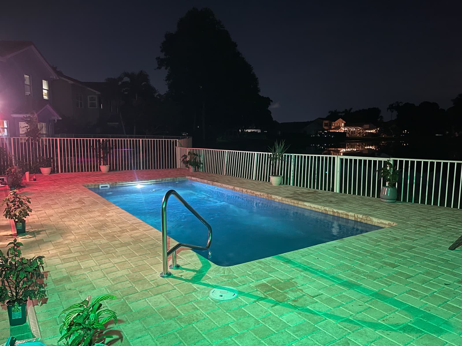 Latham Delray fiberglass pool with brick paver deck, stainless handrail and pool safety fence facing the lake in West Palm Beach FL